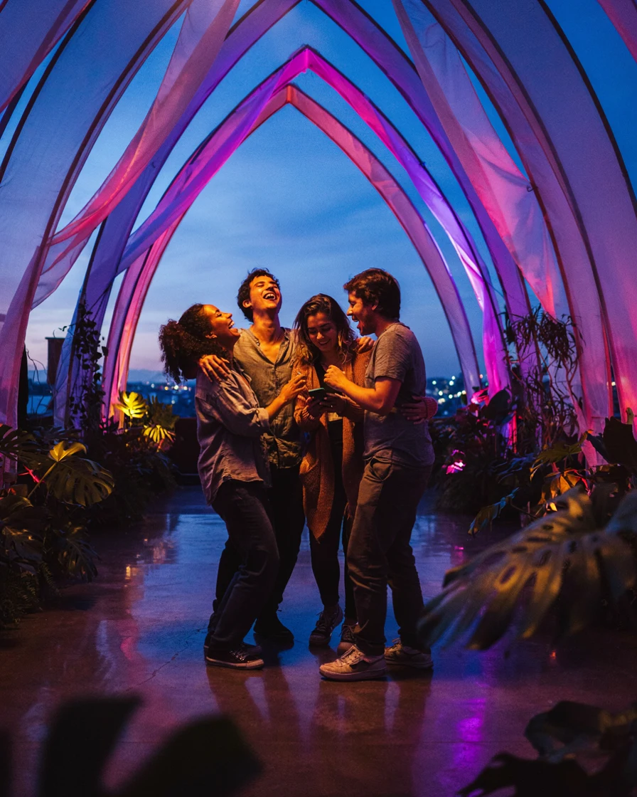 Amigos felizes sob uma instalação de luz ao anoitecer